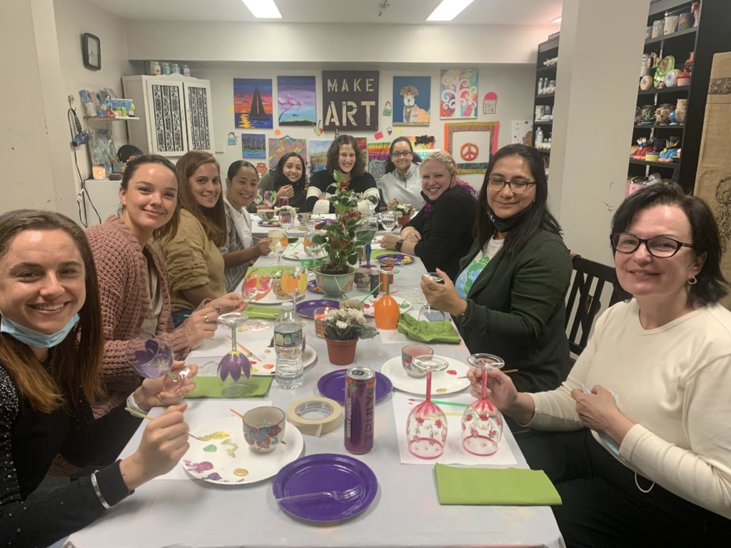 A group of people gathered around a table, each holding a wine glass that has been artistically decorated